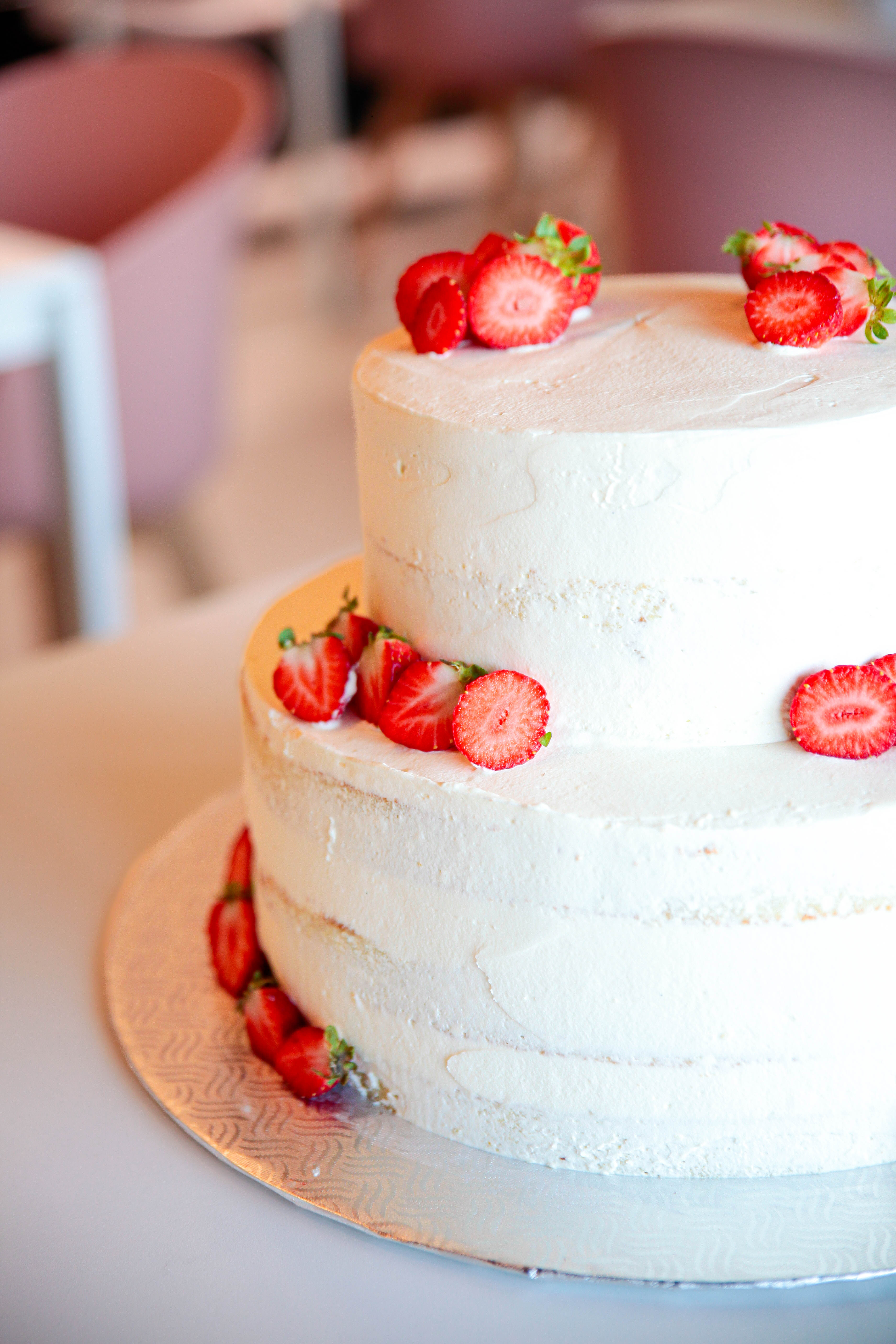 Le gâteau de mariage est un délice à deux étages recouvert de crème et décoré de fraises.